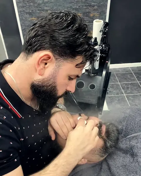 Barber arbeitet die Bartkontur eines Kunden aus