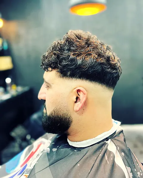 Curly Top mit Fade und sauber konturiertem Bart